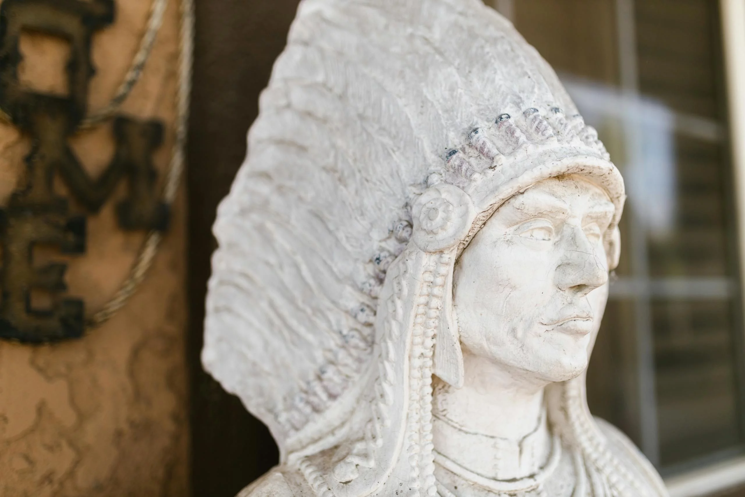Detailed close-up of a stone sculpture depicting a Native American chief with a feathered headdress